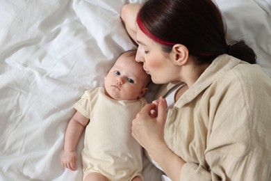 Photo of Mother with her newborn baby on bed indoors, top view. Space for text