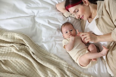 Photo of Mother with her newborn baby on bed indoors, top view. Space for text