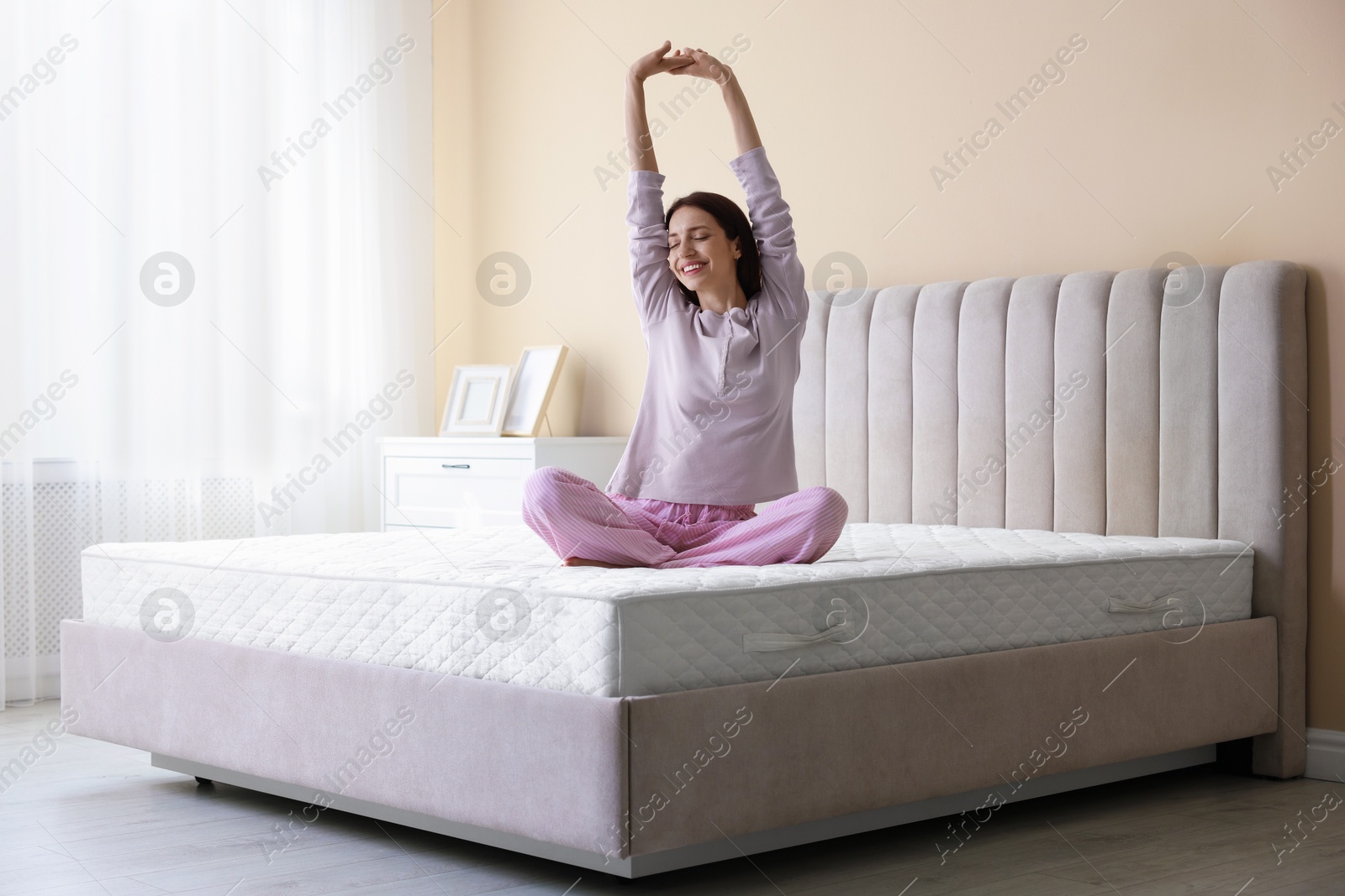 Woman stretching on bed with orthopedic mattress at home Photo of Woman stretching on bed with orthopedic mattress at home