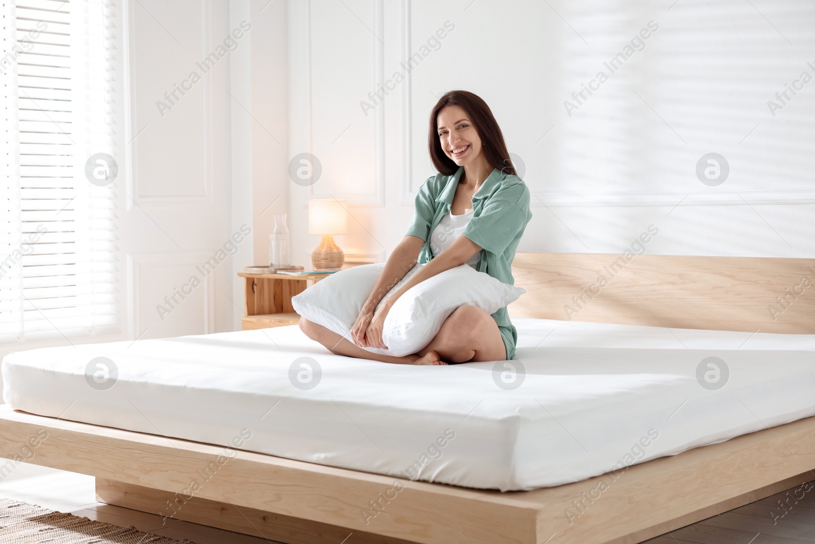 Woman on bed with soft mattress at home Photo of Woman on bed with soft mattress at home