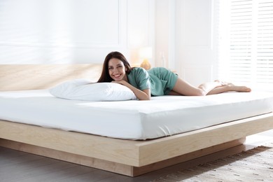 Photo of Woman lying on bed with orthopedic mattress at home