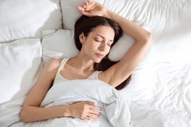 Photo of Woman sleeping on bed with soft mattress at home, top view