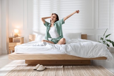 Photo of Woman stretching on bed with soft mattress at home