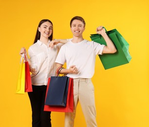 Photo of Happy couple with shopping bags on yellow background