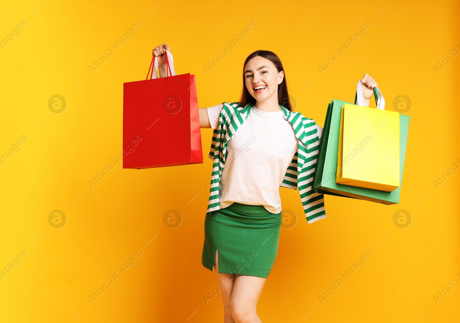 Positive woman with shopping bags on yellow background Photo of Positive woman with shopping bags on yellow background