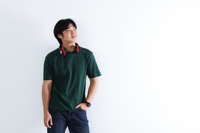 Photo of Confident Asian man with headphones on white background. Space for text