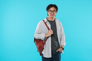 Photo of Handsome Asian man in glasses with backpack on light blue background