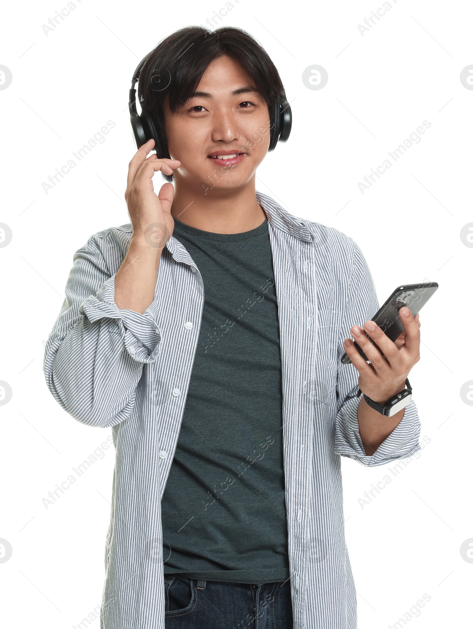 Handsome Asian man in headphones with smartphone on white background Photo of Handsome Asian man in headphones with smartphone on white background