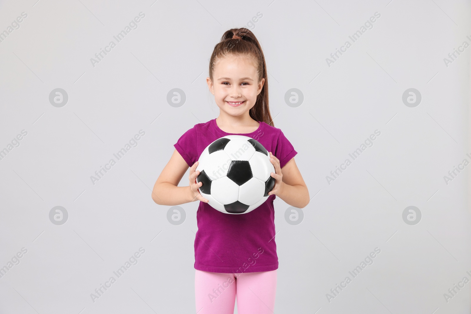 Little girl with soccer ball on light grey background Photo of Little girl with soccer ball on light grey background