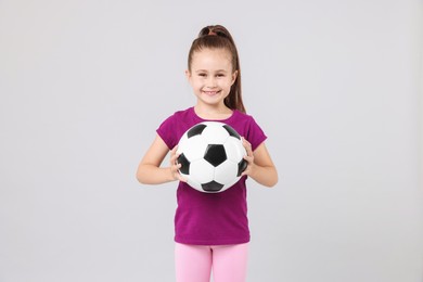 Photo of Little girl with soccer ball on light grey background