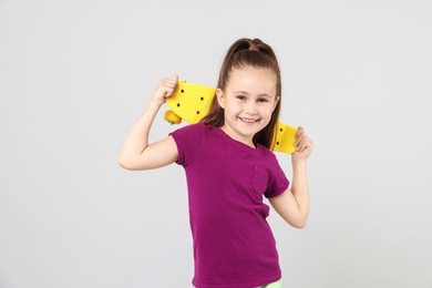 Photo of Little girl with penny board on light grey background