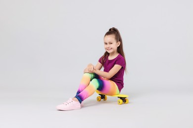 Photo of Little girl with penny board on light grey background