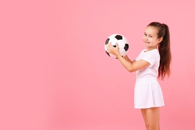 Photo of Little girl with soccer ball on pink background, space for text