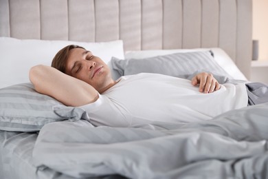 Photo of Young man sleeping on bed with soft mattress at home