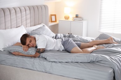 Photo of Young man sleeping on bed with soft mattress at home