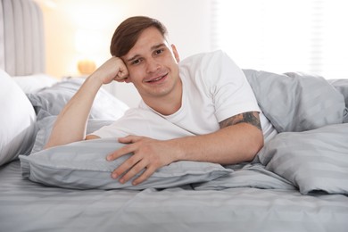 Photo of Young man lying on bed with soft mattress at home