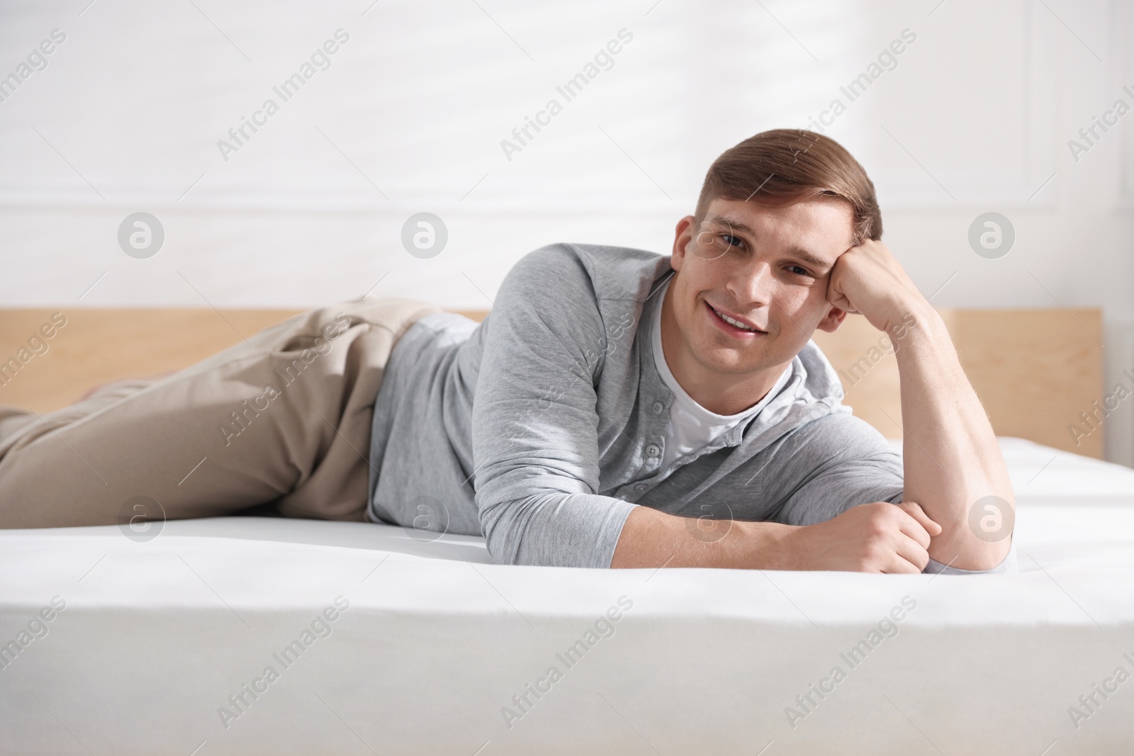 Young man lying on bed with soft mattress at home Photo of Young man lying on bed with soft mattress at home