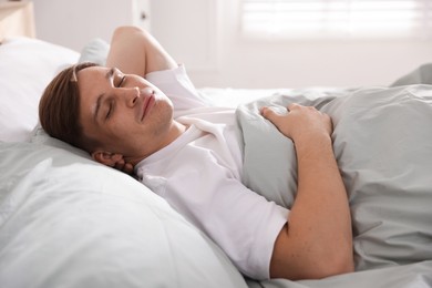 Photo of Young man sleeping on bed with soft mattress at home