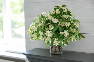 Photo of Beautiful jasmine flowers in vase fireplace indoors, space for text