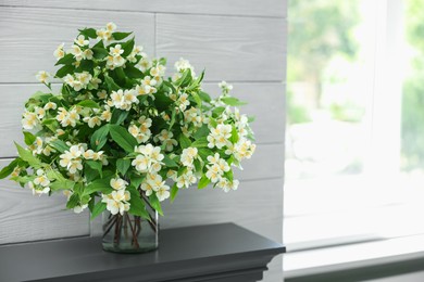Photo of Beautiful jasmine flowers in vase fireplace indoors, space for text