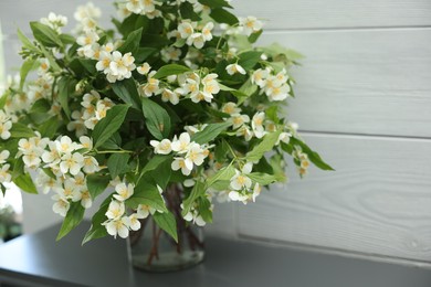 Photo of Beautiful jasmine flowers in vase fireplace indoors, closeup. Space for text