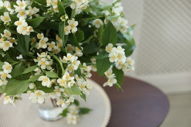 Photo of Beautiful jasmine flowers in vase on table indoors, closeup. Space for text