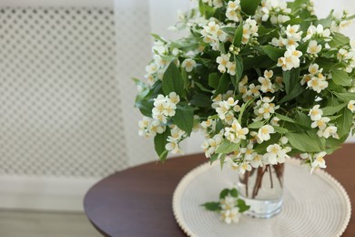 Photo of Beautiful jasmine flowers in vase on table indoors, closeup. Space for text