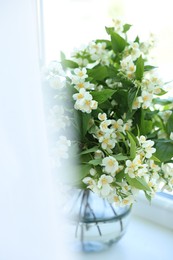Photo of Beautiful jasmine flowers in vase near window indoors, closeup