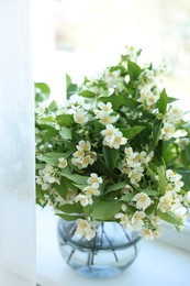 Photo of Beautiful jasmine flowers in vase near window indoors, closeup