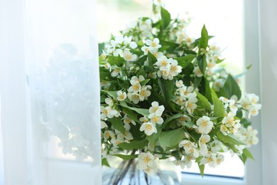 Photo of Beautiful jasmine flowers in vase near window indoors, closeup