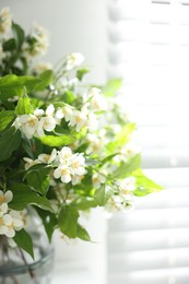 Photo of Beautiful jasmine flowers in vase near window, closeup