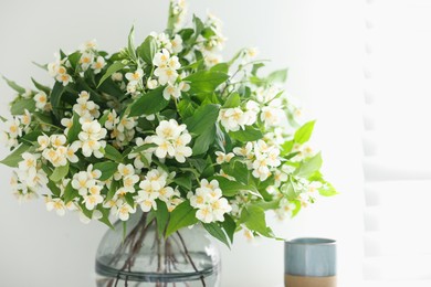Photo of Beautiful jasmine flowers in vase and decor indoors, closeup