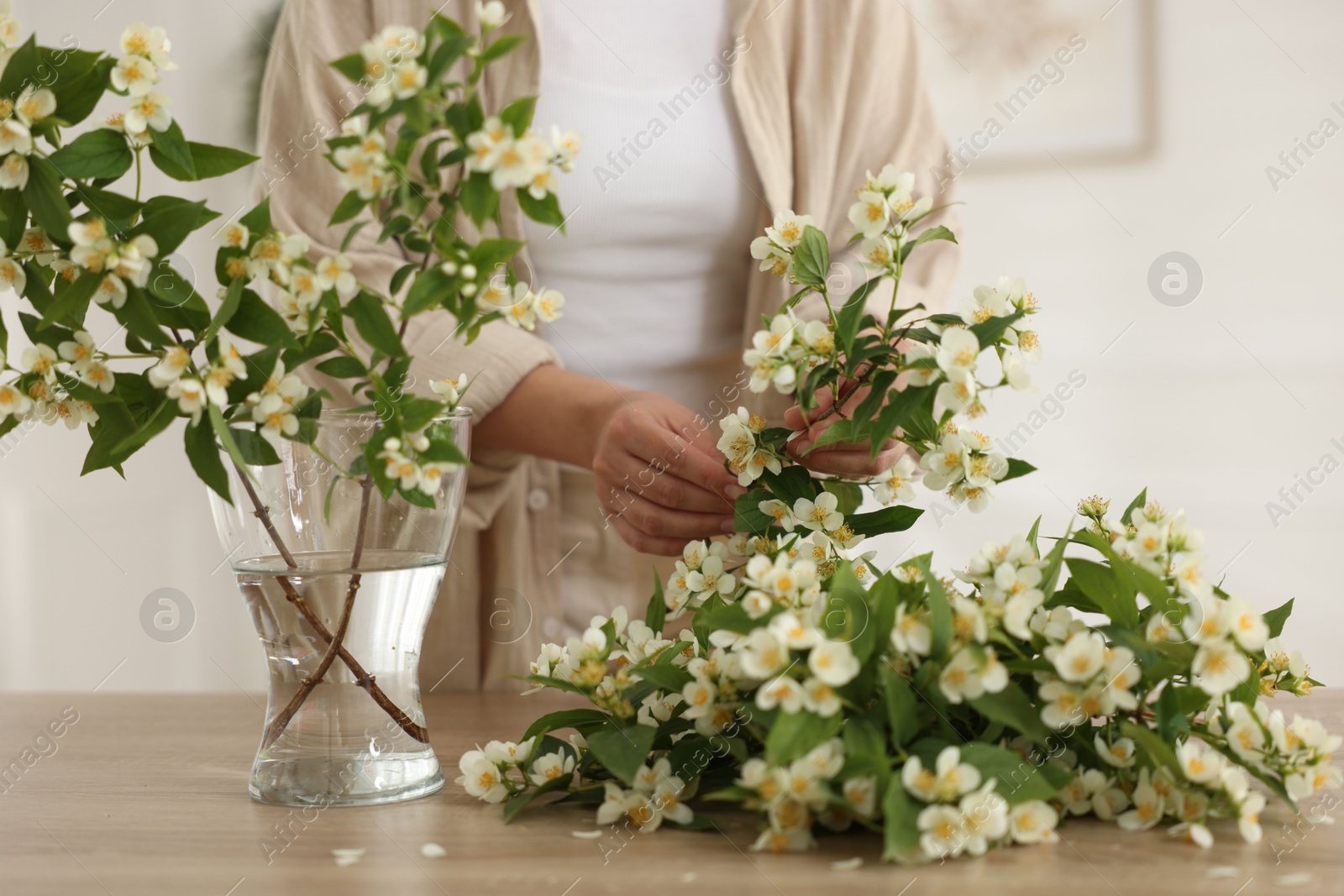 Woman making bouquet of jasmine branches at wooden table, closeup Photo of Woman making bouquet of jasmine branches at wooden table, closeup
