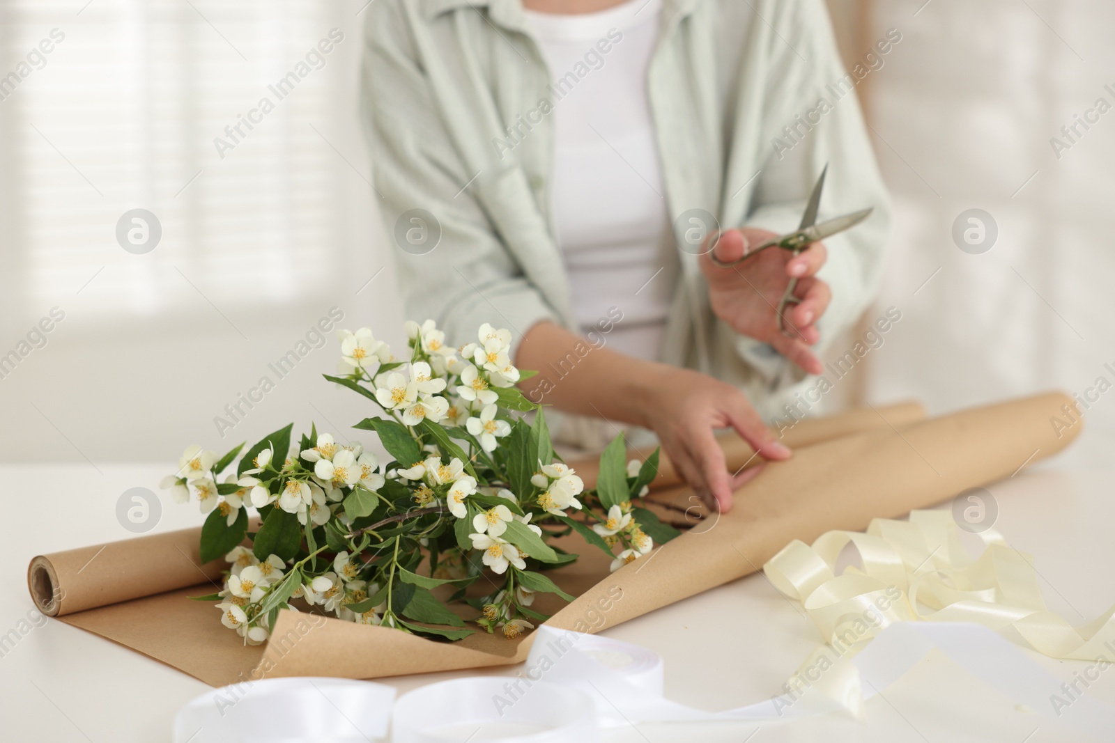 Woman making bouquet of jasmine branches at white table, closeup Photo of Woman making bouquet of jasmine branches at white table, closeup