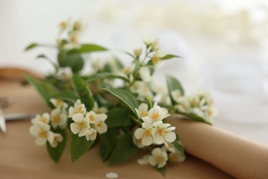 Photo of Jasmine branches and kraft paper on white table, closeup