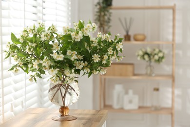 Photo of Bouquet of beautiful jasmine flowers in vase on wooden table indoors. Space for text