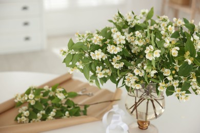 Photo of Bouquet of beautiful jasmine flowers in vase on white table indoors