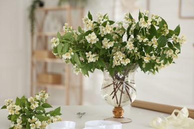 Photo of Bouquet of beautiful jasmine flowers in vase on white table indoors