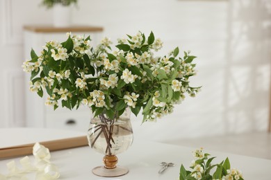 Photo of Bouquet of beautiful jasmine flowers in vase on white table indoors