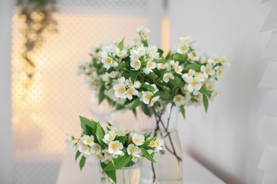 Photo of Bouquet of beautiful jasmine flowers in vase on white table indoors, closeup