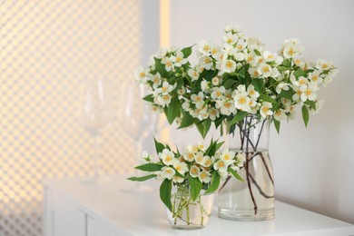 Photo of Bouquet of beautiful jasmine flowers in vase on white table indoors