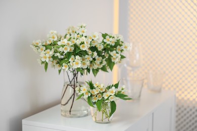 Photo of Bouquet of beautiful jasmine flowers in vase on white table indoors