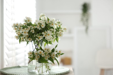 Photo of Bouquet of beautiful jasmine flowers in vase on table indoors. Space for text