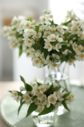 Photo of Bouquet of beautiful jasmine flowers in vase on table indoors, closeup