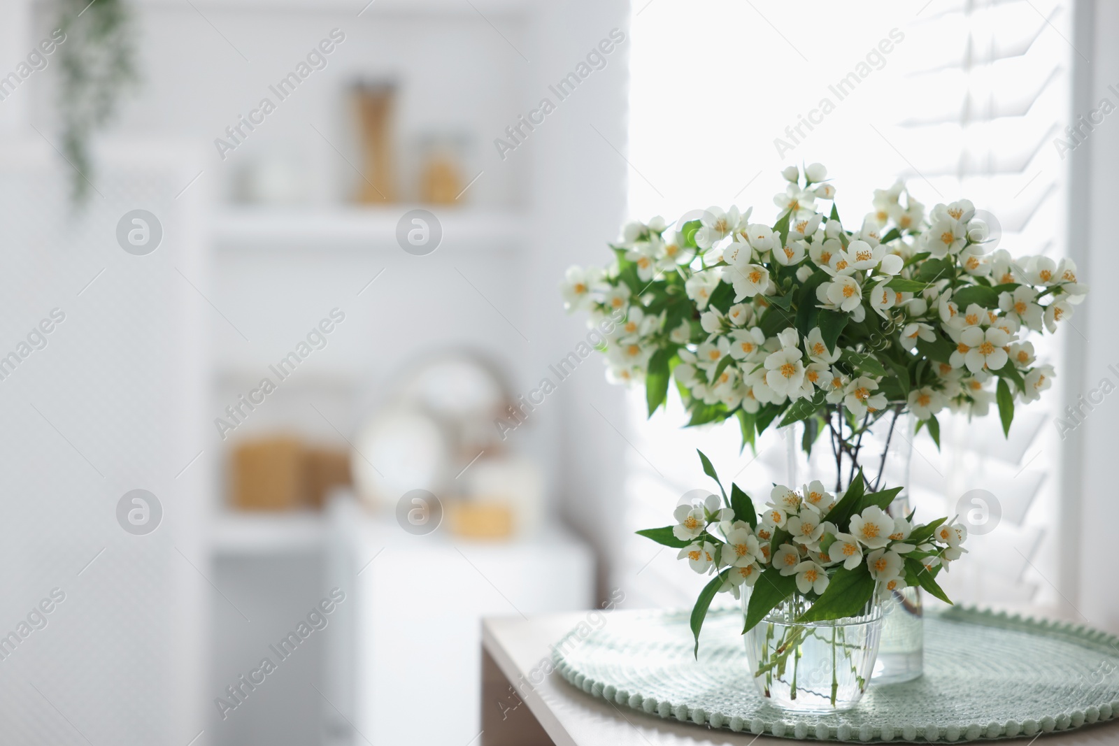 Bouquet of beautiful jasmine flowers in vase on table indoors. Space for text Photo of Bouquet of beautiful jasmine flowers in vase on table indoors. Space for text