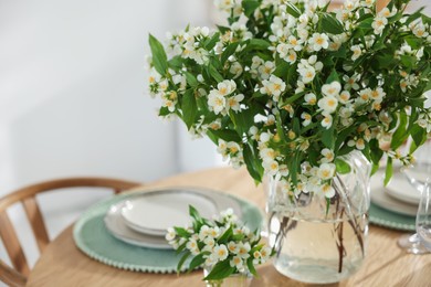 Photo of Bouquet of beautiful jasmine flowers on dining table indoors, closeup. Space for text