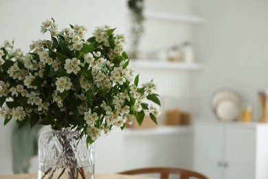 Photo of Bouquet of beautiful jasmine flowers in vase indoors, closeup. Space for text