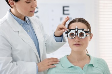 Photo of Ophthalmologist examining patient's vision with trial frame in clinic