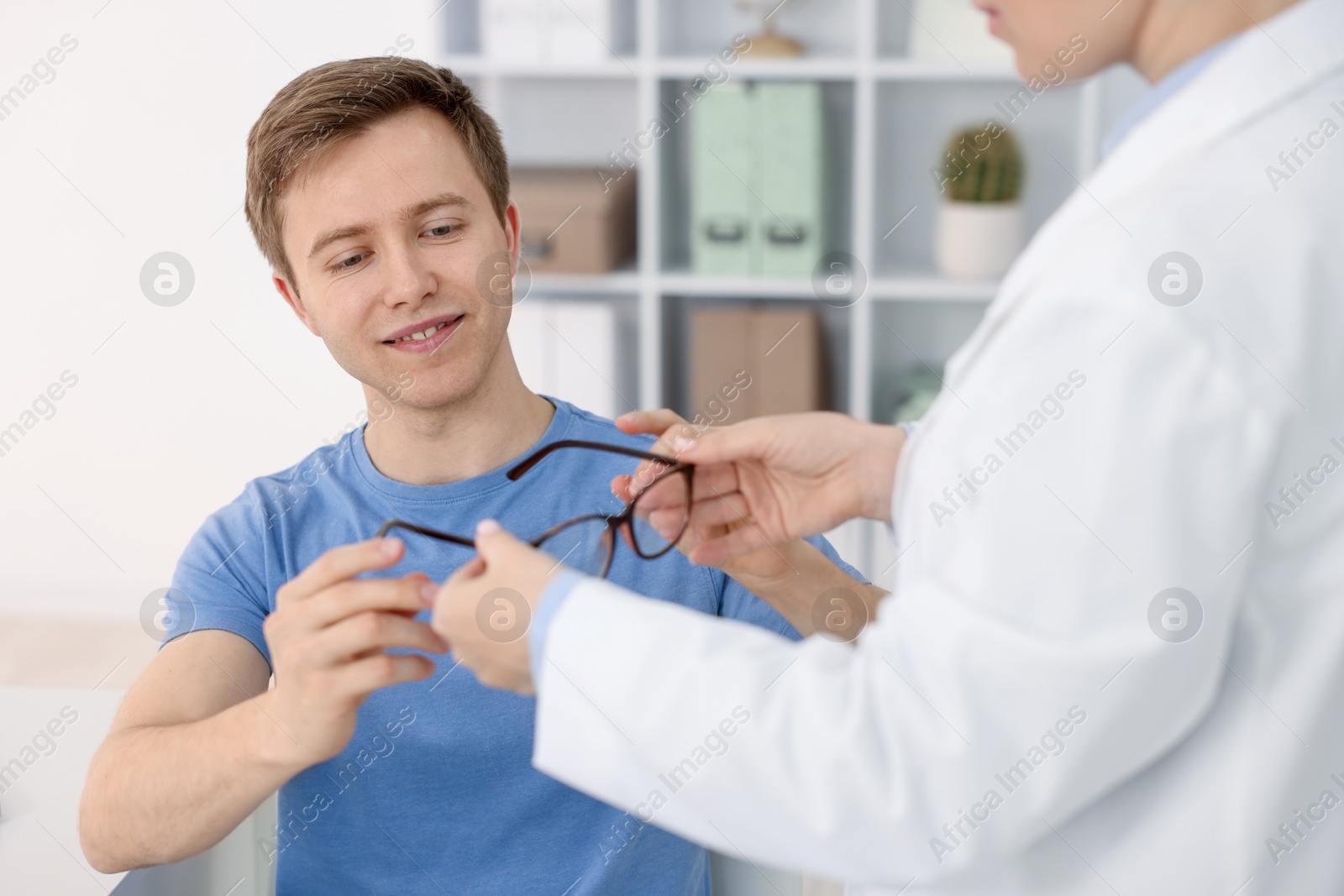 Ophthalmologist giving glasses to patient in clinic, closeup Photo of Ophthalmologist giving glasses to patient in clinic, closeup