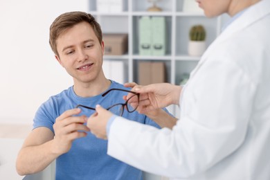 Photo of Ophthalmologist giving glasses to patient in clinic, closeup
